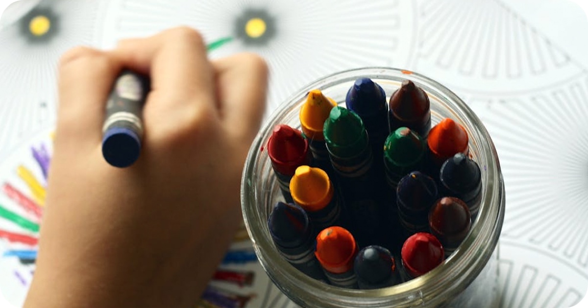 Mâna unui copil desenând cu creioane colorate, imagine din proiectul NOKIDU